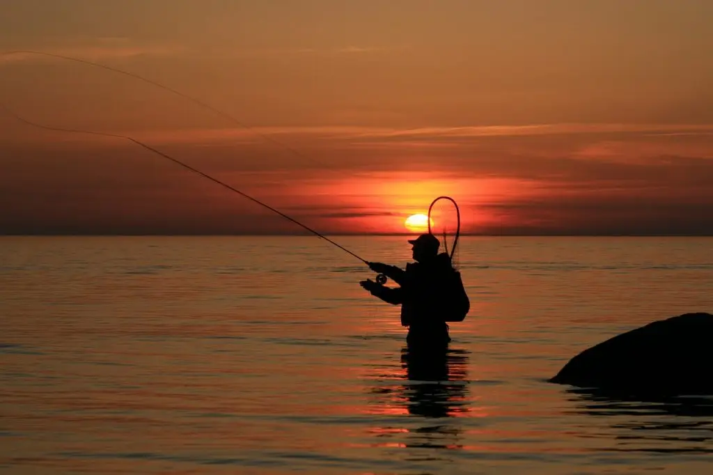couché de soleil sur l'eau avec pêcheur à la mouche