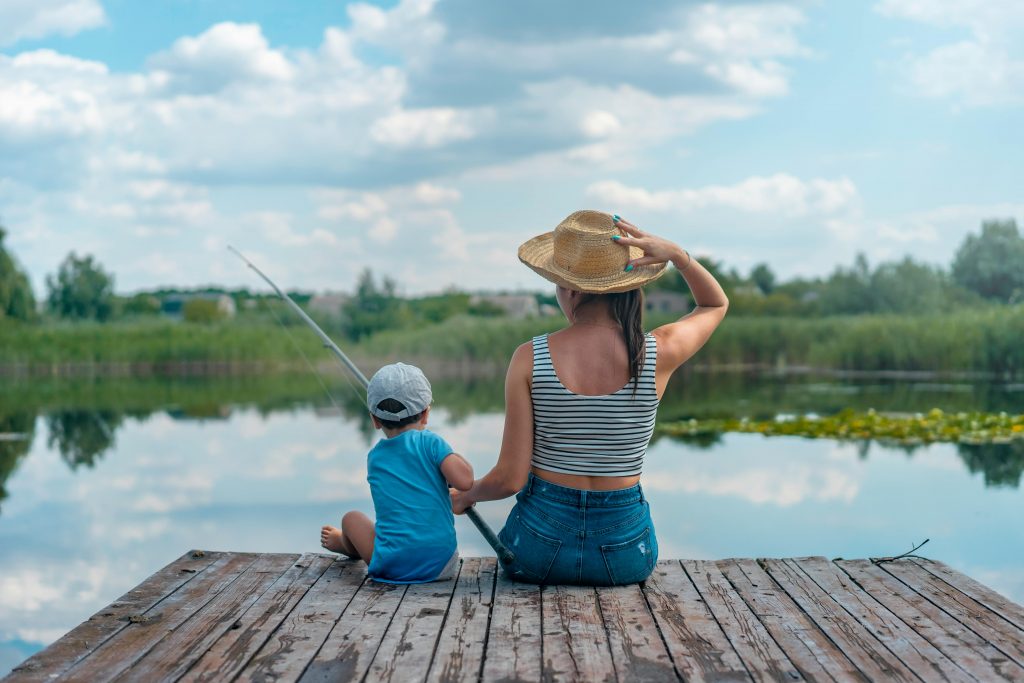 deux personnes dont un enfant assises sur un ponton en pêchant