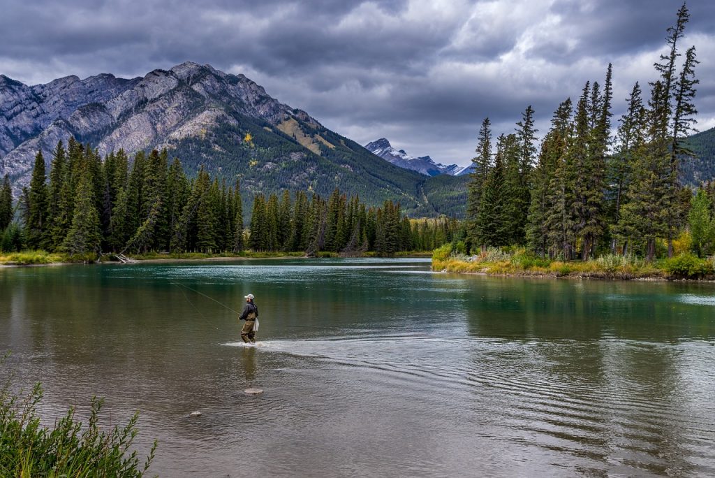 personne qui pêche dans l'eau vue montagne